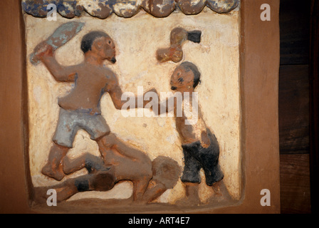 Abomey Benin Palastskulpturen von Abomey restauriert vom Getty Conservation Institute Basrelief im Palast vom Koenig Glele eines der Hauptthemen der Basreliefs in Abomey ist die Verherrlichung der militaerischen Eroberungen des Koenigreiches die Szene zeigt Gleles Pluenderung des gegnerischen Koenigreiches Keton Ein Dahome Krieger Hat einen Feind niedergeschlagen und einem anderen den Arm abgehackt Abomey Benin Palace sculture di Abomey restaurate dal Getty Conservation Institute Bas Relief nel palazzo di Re Glele uno dei temi principali del Abomey bassorilievi è la glorificazione Foto Stock