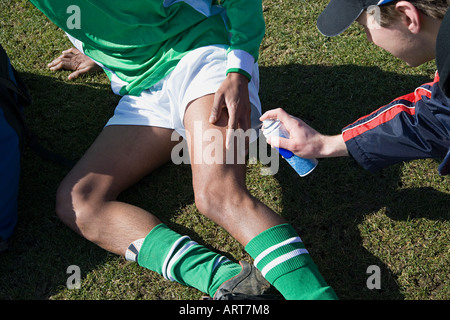 Feriti il calciatore avente la sua gamba spruzzata Foto Stock