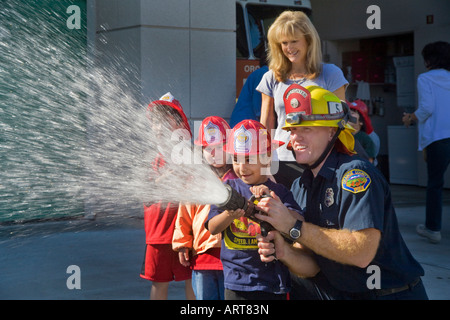 Una scuola elementare boy diventa una possibilità di spruzzare una manichetta antincendio Foto Stock