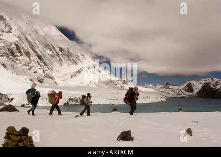 I facchini che trasportano carichi attraverso la neve Tilicho Lake trekking nella regione di Annapurna del Nepal. Foto Stock