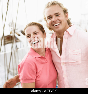 Coppia giovane in piedi con le braccia intorno a ogni altro e sorridente Foto Stock