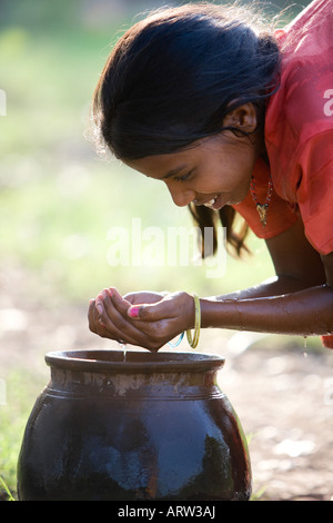 Ragazza indiana acqua potabile da una pentola di creta in campagna. Andhra Pradesh, India Foto Stock