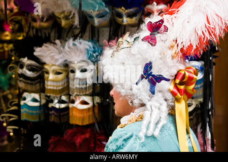 Persona vestito in costume carvial e parrucca passa alla vetrina di un negozio di maschere di vendita Piazza San Marco Veneto Italia Foto Stock