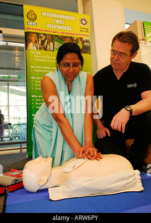 50 anni di potenziale volontario asiatici First Responder di apprendimento di tecniche di rianimazione a St John Ambulance servizio volontario. Foto Stock