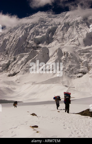 I facchini che trasportano carichi attraverso la neve Tilicho Lake trekking nella regione di Annapurna del Nepal. Foto Stock