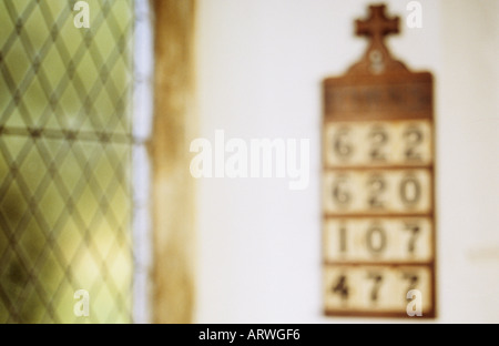 Scheda impressionistica indicando inno selezionato numeri e appeso a una parete bianca accanto a un diamante vetro piombato Foto Stock