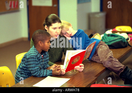 L insegnante e gli studenti la lettura di libro in dopo il programma della scuola di età compresa tra i 6 e 23. St Paul Minnesota USA Foto Stock