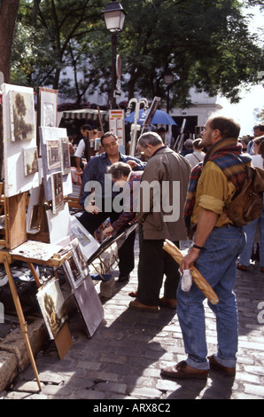 Paris Montmartre Place Du Tertre gli artisti lavorano sul display per acquisto comprende l uomo in possesso di una baguette Foto Stock