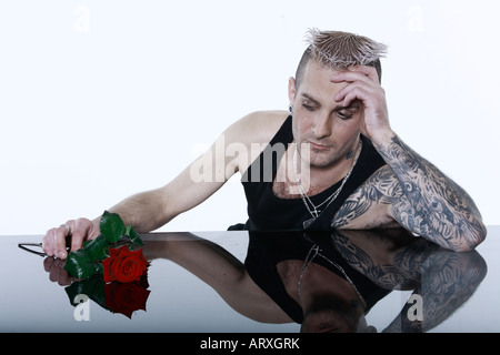 Studio shot di un triste uomo romantico con tatuaggi e piercing Foto Stock