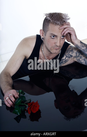 Studio shot di un triste uomo romantico con tatuaggi e piercing Foto Stock