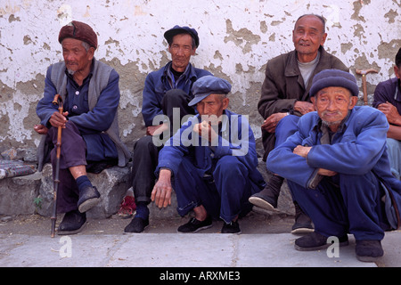 Il cinese uomini rannicchiati contro il muro a Lago Erhai village vicino alla città di Dali in Yunnan in Cina 2004 Foto Stock