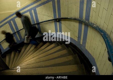 Pendolari che camminano lungo la scala a chiocciola piastrellata sulla rete metropolitana di Londra, per evitare di aspettare l'ascensore, in stazione senza scale mobili. Foto Stock