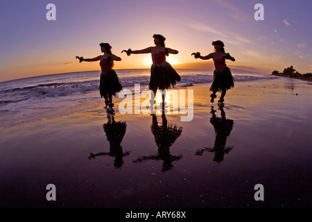 Tre danzatori di hula si stagliano da un sole di setting a Olowalu, Maui. Foto Stock