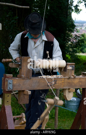 Artigiano al lavoro su un manualmente alimentato tornio in legno a una festa del bosco Foto Stock