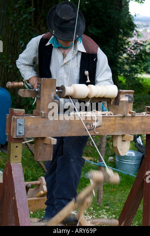 Artigiano al lavoro su un manualmente alimentato tornio in legno a una festa del bosco Foto Stock