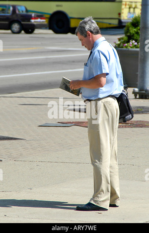 Un lavoratore della città la lettura di un libro in attesa di un autobus in Downtown Dayton Ohio Foto Stock