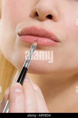 Donna s le labbra con il rossetto spazzola Foto Stock