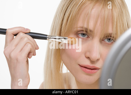 Donna con spazzola di cosmetici e specchio Foto Stock