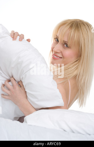 Donna che gioca con cuscino nel letto Foto Stock