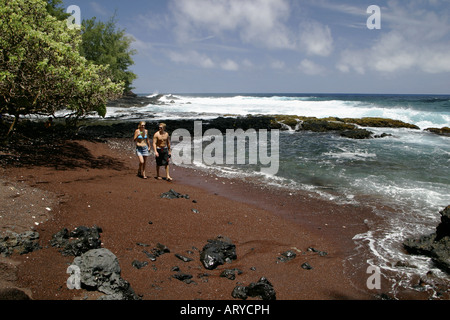 Giovane gode appartato lungomare a piedi su invitante & unique la spiaggia di sabbia rossa Kaihalulu baia ad appena pochi passi di distanza dalla città di Hana Foto Stock