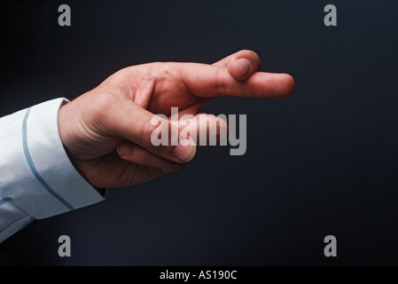 Dita incrociate per buona fortuna stagliano su sfondo nero Foto Stock