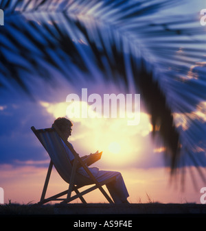 mature woman reading alone on tropical beach Foto Stock