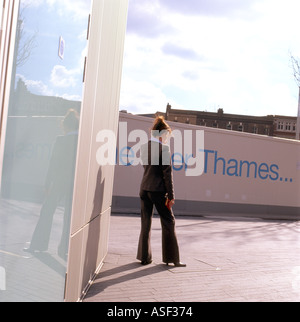 Una femmina di lavoratore di ufficio in un vestito di fumare al di fuori di un edificio per uffici a London Bridge, London, Regno Unito Foto Stock