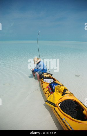 Un pescatore a mosca si siede sul suo kayak selezionando una mosca per bonefishing nelle isole exuma bahamas Foto Stock