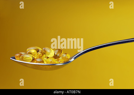 Un cucchiaio colmo di integratori contro un sfondo giallo Foto Stock