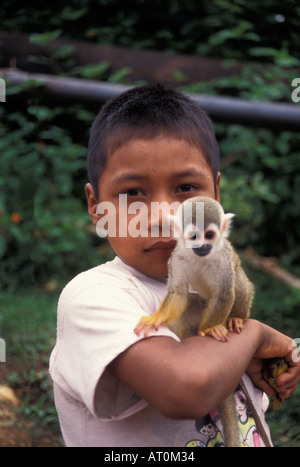 Captive Scimmia di scoiattolo Saimiri sciureus con un giovane ragazzo nativo nella foresta pluviale dell'Amazzonia ecuadoriana America del Sud Foto Stock