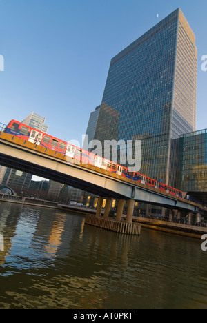 Verticale ampia angolazione di una Docklands Light Railway treno [DLR] lasciando Heron Quays station su una luminosa giornata di sole. Foto Stock