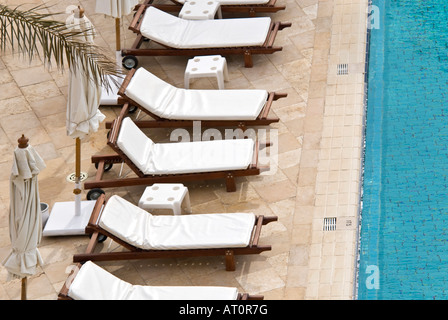 Sopraelevata orizzontale in prossimità di una fila di vuoto bianco pulito lettini disposti intorno alla piscina di un hotel a 5 stelle hotel nominale Foto Stock