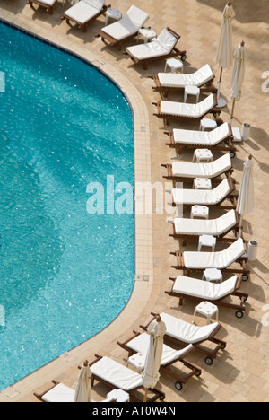 Vista verticale del vuoto bianco pulito lettini disposti intorno alla piscina di un hotel a 5 stelle hotel nominale. Foto Stock