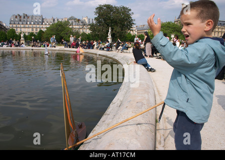 Piccolo Ragazzo con barca giocattolo nella fontana nel Jardin des Tuileries Parigi Foto Stock