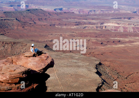 Donna seduta sul bordo di una scogliera, il Parco Nazionale di Canyonlands, Utah, Stati Uniti d'America Foto Stock