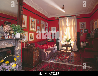 Tende di color crema in rosso livingroom con moquette a motivi geometrici e foto sopra il divano Foto Stock