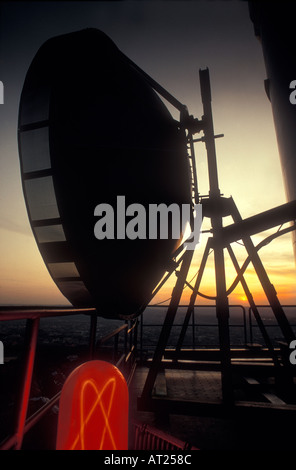 Comunicazione piatto sulla parte superiore della torre radio al tramonto Foto Stock