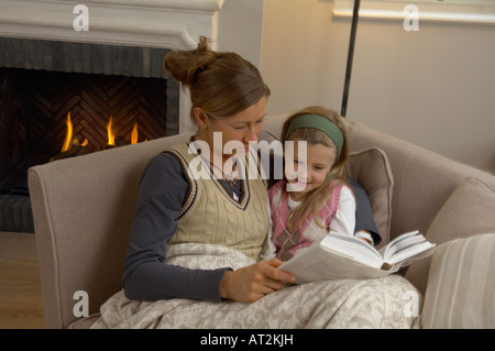 Madre e figlia leggendo un libro nel salotto - Germania. Foto Stock