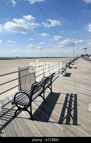 Righe di panchine sul lungomare a Coney Island, con il famoso Parachute Jump ride in background, New York Foto Stock