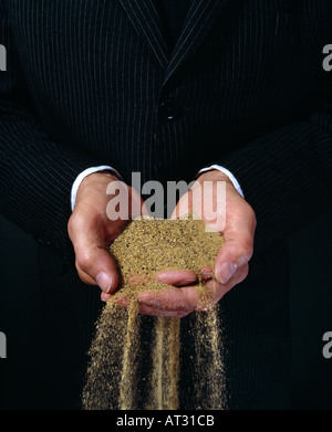 Imprenditore con versamento di sabbia dalle sue mani Foto Stock