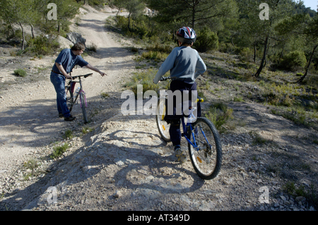 Francia Provenza Vitrolles giovane ragazzo e padre s amico cavalcare le loro mountain bike su una strada sterrata Foto Stock