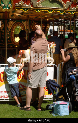 Un padre onde ai suoi figli in sella a una giostra presso il villaggio di innocenti FETE IN Regents Park Londra 2007 Foto Stock