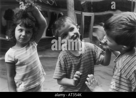 Un ragazzo e una ragazza facendo facce in uno specchio Foto Stock