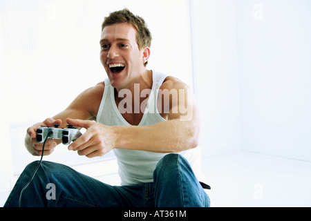 Un uomo seduto sul pavimento a giocare su una console di gioco Foto Stock