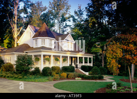 Fall folliage circonda un bianco grande storia di due borghesia suburbana a casa con le torrette e un grande portico anteriore Foto Stock