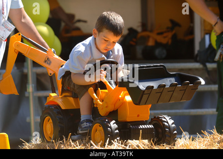 Un padre aiuta il suo bambino gioca su un giocattolo DIGGER presso il villaggio di innocenti FETE IN Regents Park Londra 2007 Foto Stock