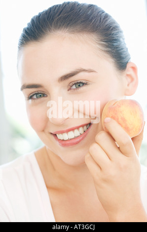 Giovane donna tenendo un peach, sorridente Foto Stock
