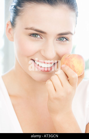Giovane donna tenendo un peach, sorridente Foto Stock
