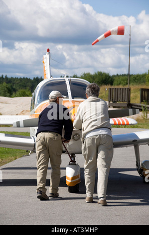 Due uomini spingendo un piccolo aeroplano verso la pista Foto Stock