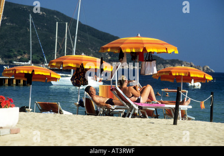 I turisti prendere il sole sulla spiaggia della Biodola sotto colorati ombrelloni,Isola d'Elba. Foto Stock